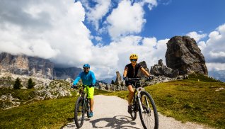 Radfahren in Cortina d'Ampezzo, mit Cinque Torri und Tofana im Hintergrund © Gorilla - stock.adobe.com